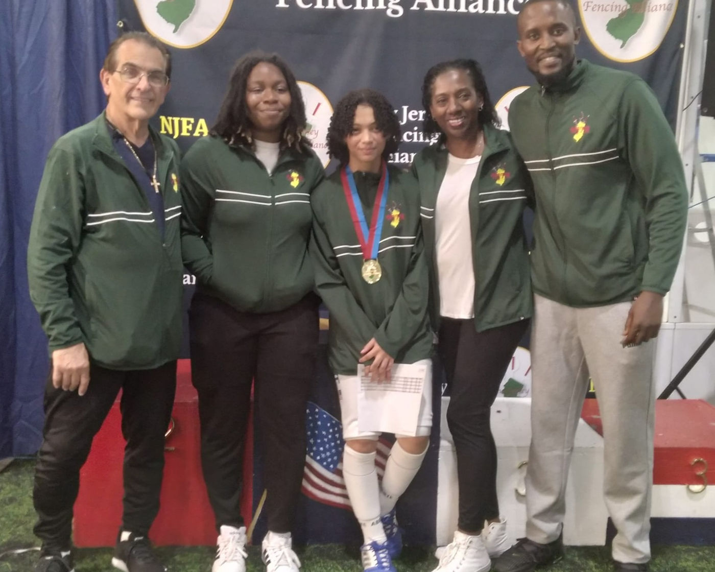 NJFA coaches and a medal-winning fencer in team jackets